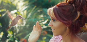 Lindsey Stirling in her video "Lost Girls" looking at a hummingbird